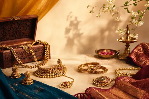 Traditional Indian jewellery arranged with a necklace, bangles, earrings, maang tikka, silk fabric and diya decor for a beginner cultural guide.